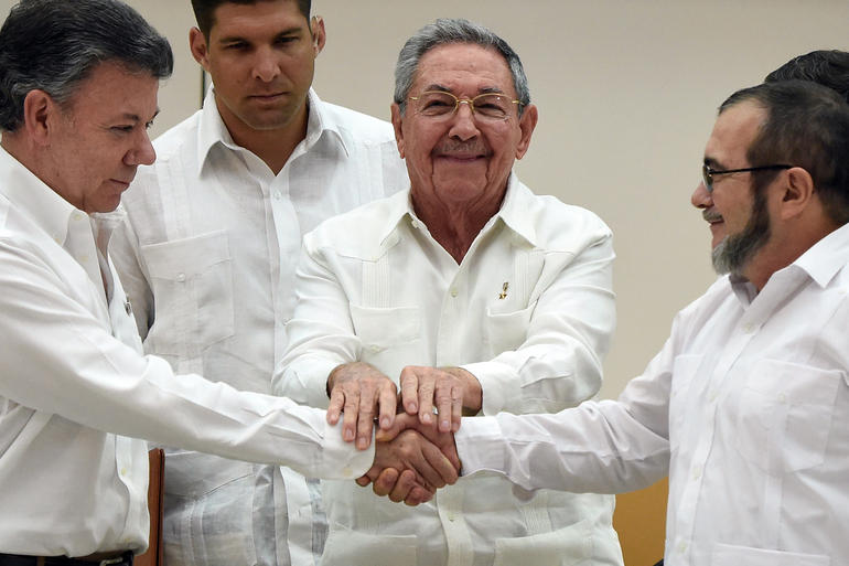 TOPSHOTS Colombian President Juan Manuel Santos (L) and the head of the FARC guerrilla Timoleon Jimenez, aka Timochenko (R), shake hands as Cuban President Raul Castro (C) holds their hands during a meeting in Havana on September 23, 2015. The Colombian government and FARC rebels announced a key breakthrough in their nearly three-year peace talks Wednesday with the signing of a deal on justice for crimes committed during the five-decade conflict. The deal includes the creation of special courts and a broad amnesty, though this will not cover "crimes against humanity, serious war crimes" and other offenses including kidnappings, extrajudicial executions and sexual abuse, said officials from Cuba and Norway, the guarantors in the talks. AFP PHOTO / Luis Acosta